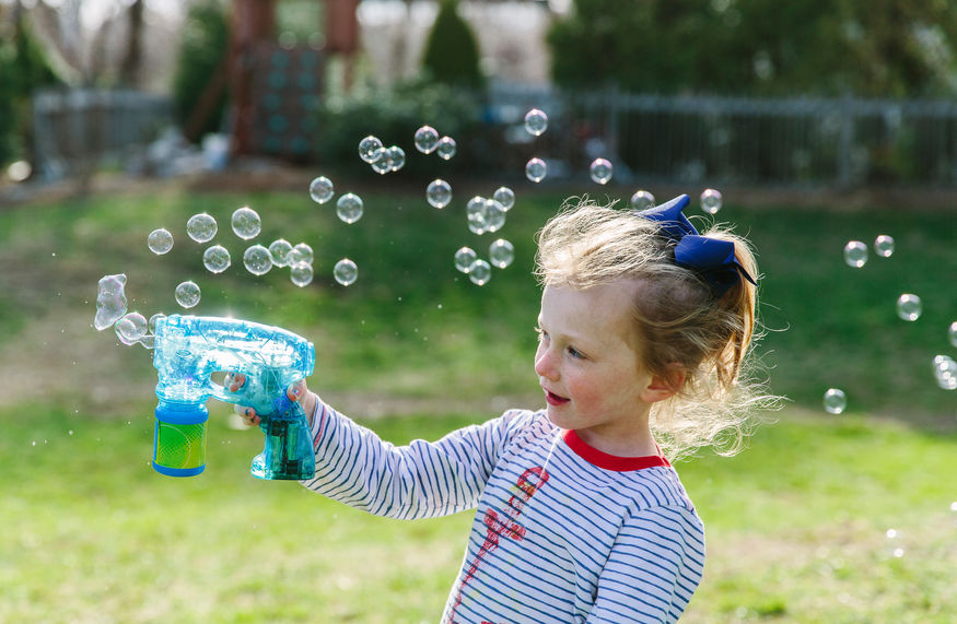 Young girl playing with a bubble maker.